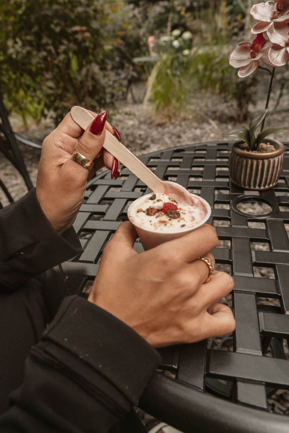 A guest at an outdoor patio table eating a strawberry parfait with a wooden spoon